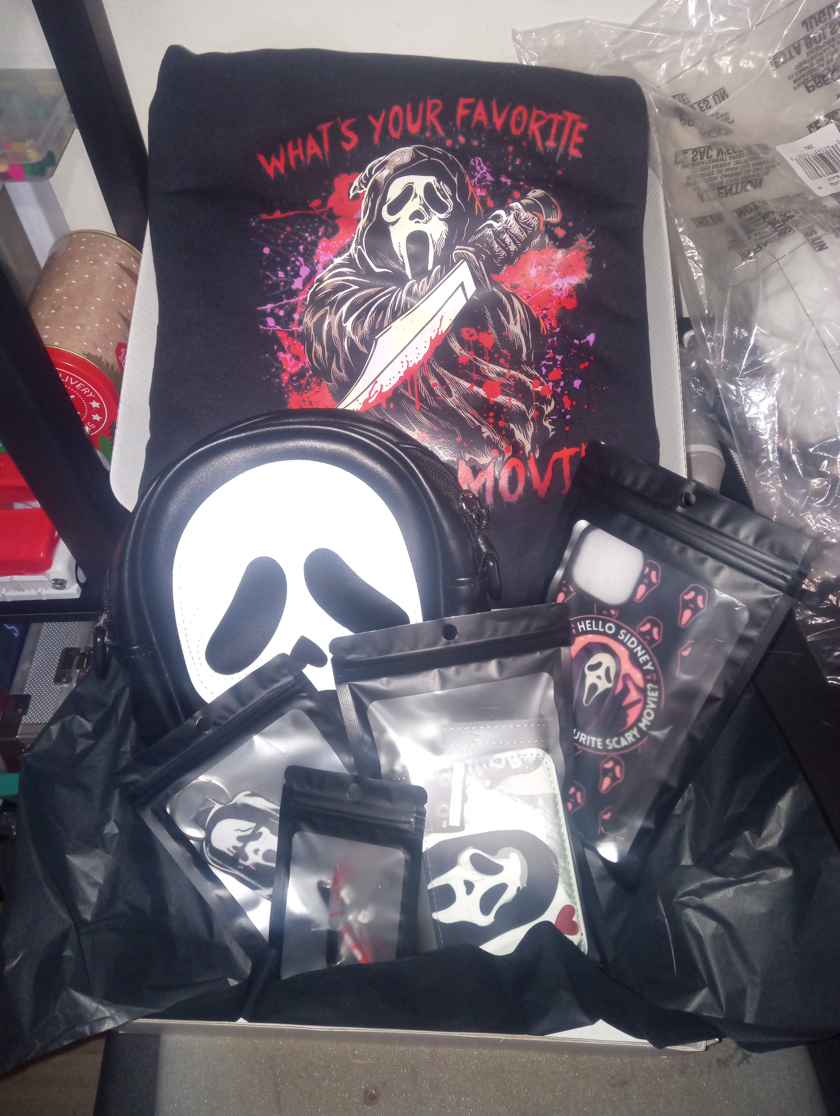 Black t-shirt with graphic design and text, surrounded by other merchandise on a table.